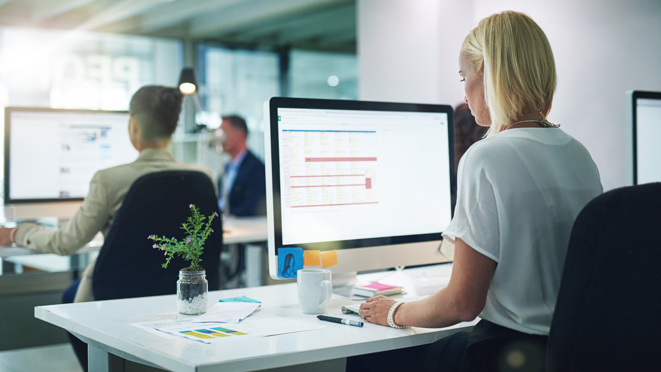 Generische Officeszene: Frau sitzt vor Bildschirm Kachel Vorschau